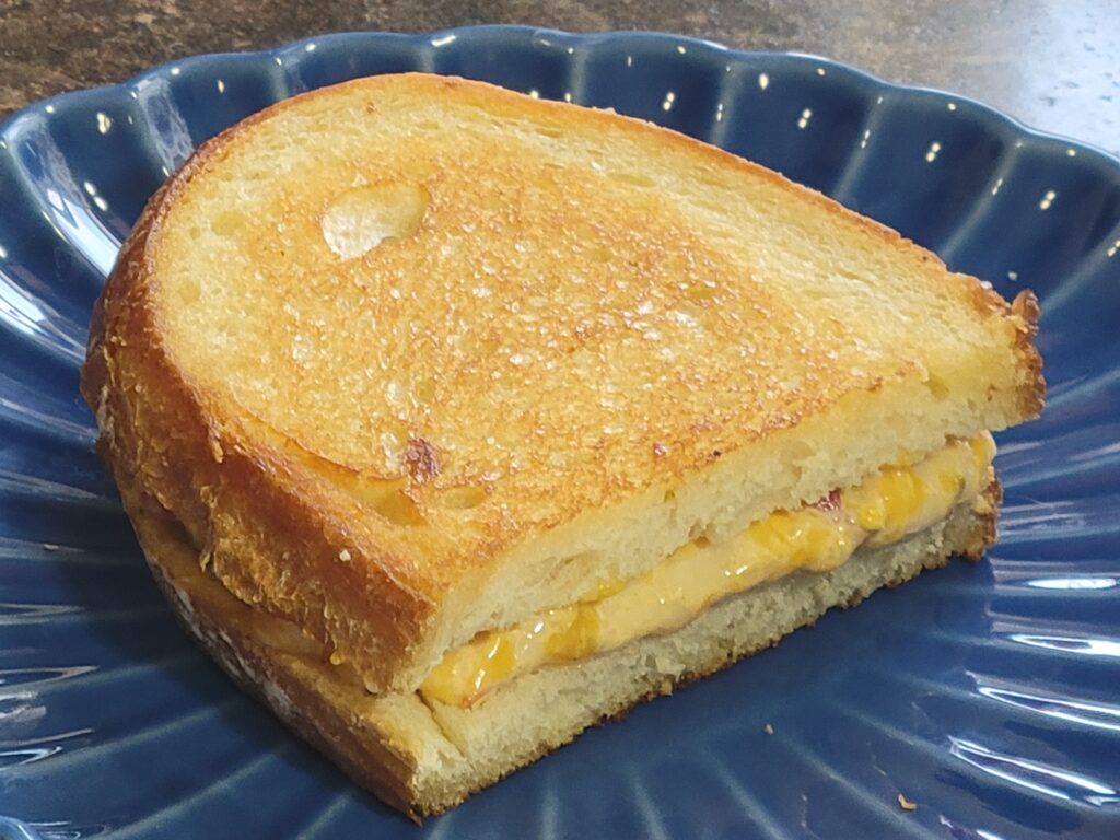 Grilled pimiento cheese sandwich on golden toasted sourdough bread with melted cheese filling